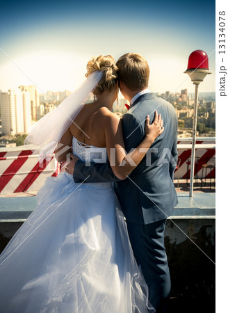 Just married couple standing on the roof and looking at urban ci 13134078