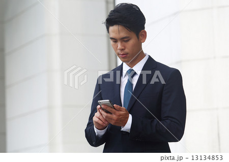 携帯をいじるアジア人男性の写真素材