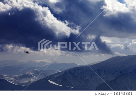 Helicopter in winter mountains and cloudy sky 13143831