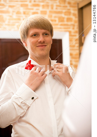 portrait of handsome young man putting on red bow tie portrait of handsome young man putting on red bow tie 13144766