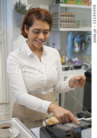 An Asian waitress receiving payment through credit card. 13145449