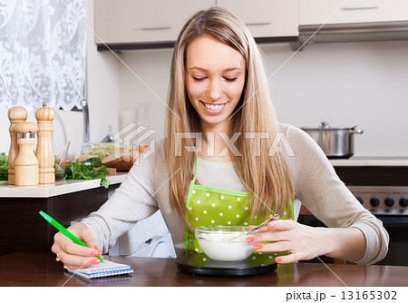 Happy woman weighing cottage cheese 13165302