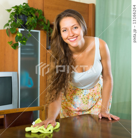 young woman dusting wooden table young woman dusting wooden table 13166264