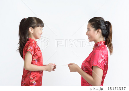 Young chinese mother in cheongsam giving daughter new year red packet isolated white background Young chinese mother in cheongsam giving daughter new year red packet isolated white background 13171357
