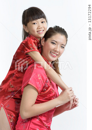 Young Chinese mother in cheongsam piggyback daughter isolated white background Young Chinese mother in cheongsam piggyback daughter isolated white background 13172294