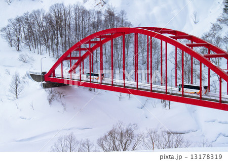 新潟県魚沼市 豪雪地を走る観光バスと赤い橋の写真素材