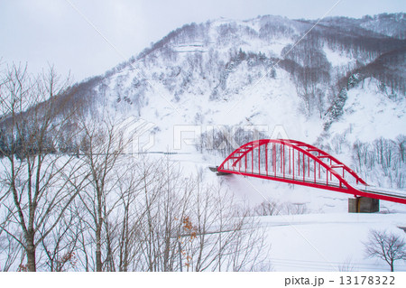 新潟県魚沼市　豪雪地の赤い橋のある風景 13178322