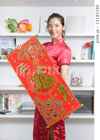 One young Chinese woman in cheongsam holding 5 good fortunes red banner in front of bookshelf 13195280
