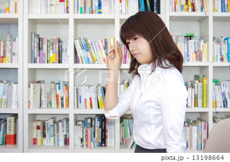 ボールペンと書棚の前の女性 白のブラウス 13198664