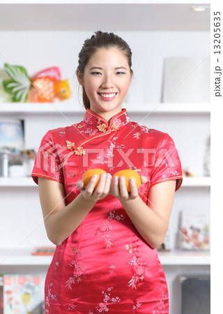 Young chinese woman in cheongsam holding oranges in front of bookshelf Young chinese woman in cheongsam holding oranges in front of bookshelf 13205635