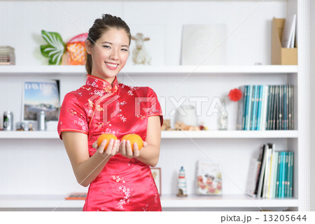 Young chinese woman in cheongsam holding oranges in front of bookshelf Young chinese woman in cheongsam holding oranges in front of bookshelf 13205644