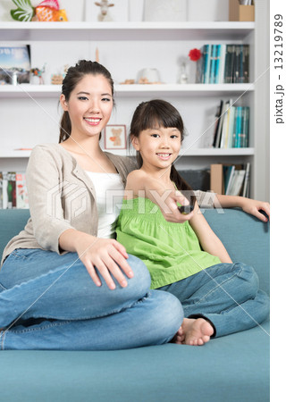 Young chinese mother and daughter watching TV at home 13219789