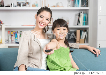Young chinese mother and daughter watching TV at home 13219793