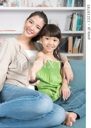 Young chinese mother and daughter watching TV at home 13219795