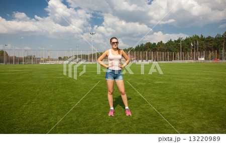 slim woman standing on soccer field at sunny day 13220989