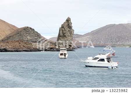 南米エクアドルの太平洋上に浮かぶ生物進化論の島、ガラパゴス諸島のサンチアゴ島を向こうに臨むバルトロメ島の美しい海の風景と観光客の見学の観光船で賑わう入江 13225982