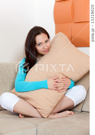 Woman sitting on a sofa with a pillow Woman sitting on a sofa with a pillow 13228020