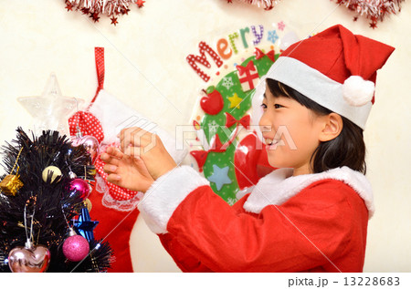 クリスマスツリーに飾り付けをするサンタクロース衣装の女の子 13228683