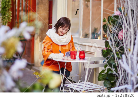 Cheerful girl writing Christmas cards in cafe Cheerful girl writing Christmas cards in cafe 13228820