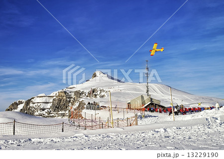 Yellow airplane flying over alpine resort in swiss alps in winte 13229190