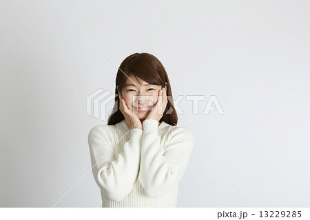 頬に手をやる笑顔の若い女性の写真素材