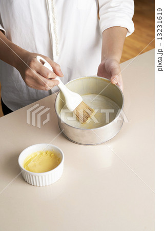 Hand brushing butter inside cake tray 13231619