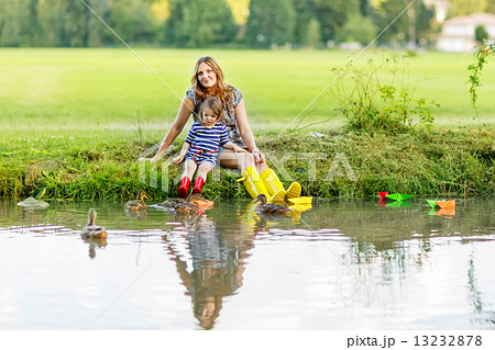 Adorable little girl and her mom playing with paper boats in a r Adorable little girl and her mom playing with paper boats in a r 13232878