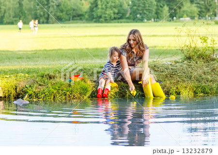 Adorable little girl and her mom playing with paper boats in a r 13232879