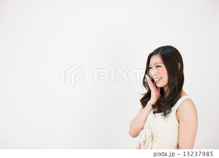 手を口にあてて笑う横顔の若い女性の写真素材