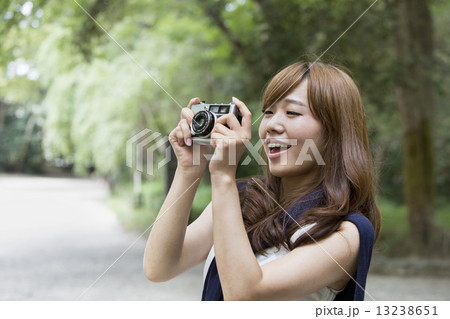 A woman in a Kyoto park holding a camera. 13238651