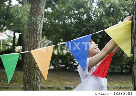 A woman in a Kyoto park holding up a colourful row of flags. A woman in a Kyoto park holding up a colourful row of flags. 13238681