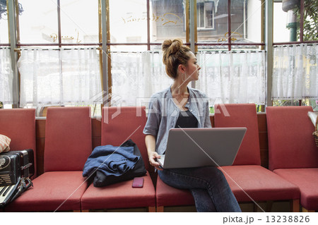 A woman working on a laptop and sitting indoors. 13238826