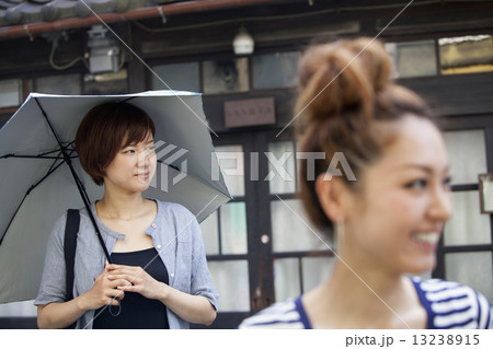 Two women standing outdoors, one holding an umbrella. 13238915