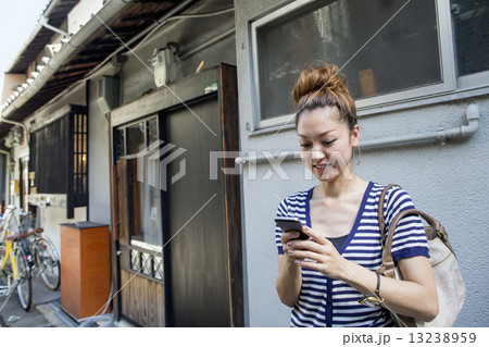 Woman standing outdoors, looking at cellphone. 13238959