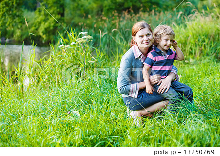 Little boy and his mother sitting on grass in summer forest Little boy and his mother sitting on grass in summer forest 13250769