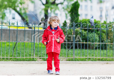 Cute little  boy catching and playing with pigeons in city 13250799
