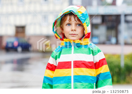 Happy smiling little boy walking in city through rain Happy smiling little boy walking in city through rain 13250875