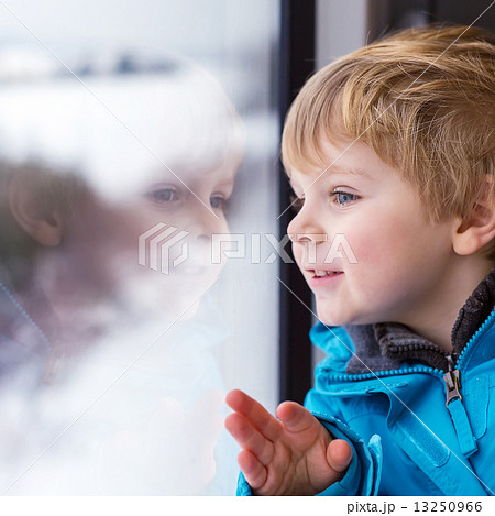 Beautiful toddler boy looking out train window outside and trave 13250966