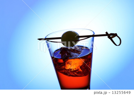 Short drink glass with red liquid, olive, ice cubes 13255649