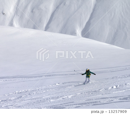 Snowboarder downhill on off piste slope with newly fallen snow 13257909