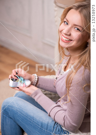 Young attractive woman holding baby shoe, interior shot Young attractive woman holding baby shoe, interior shot 13258973