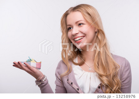 Young attractive woman holding baby shoe isolated on white backg Young attractive woman holding baby shoe isolated on white backg 13258976