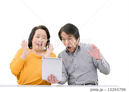 タブレットを操作している、カジュアルウェアー姿の中年夫婦の白抜きポーズ 13263796