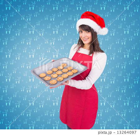 Composite image of brunette in santa hat offering hot cookies Composite image of brunette in santa hat offering hot cookies 13264097