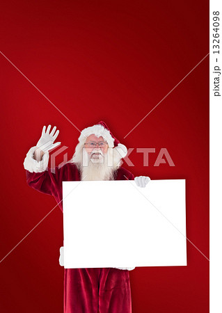 Composite image of santa holds a sign and is waving 13264098