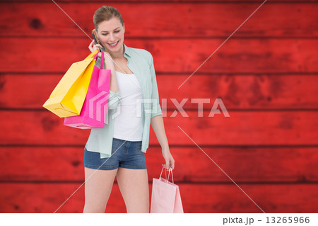 Composite image of happy blonde holding shopping bags and talkin Composite image of happy blonde holding shopping bags and talkin 13265966