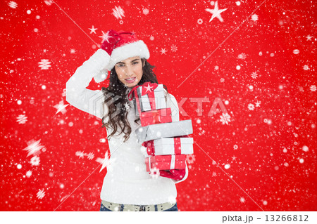 Composite image of stressed brunnette in santa hat holding gifts 13266812