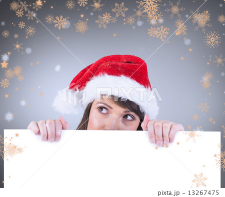 Composite image of festive brunette holding a poster while looki Composite image of festive brunette holding a poster while looki 13267475