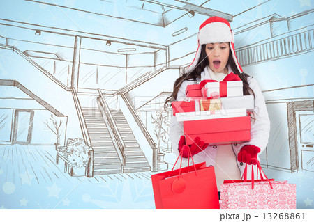 Composite image of surprised brunette in winter clothes holding Composite image of surprised brunette in winter clothes holding 13268861