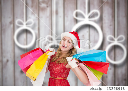 Composite image of excited blonde in santa hat holding shopping Composite image of excited blonde in santa hat holding shopping 13268918